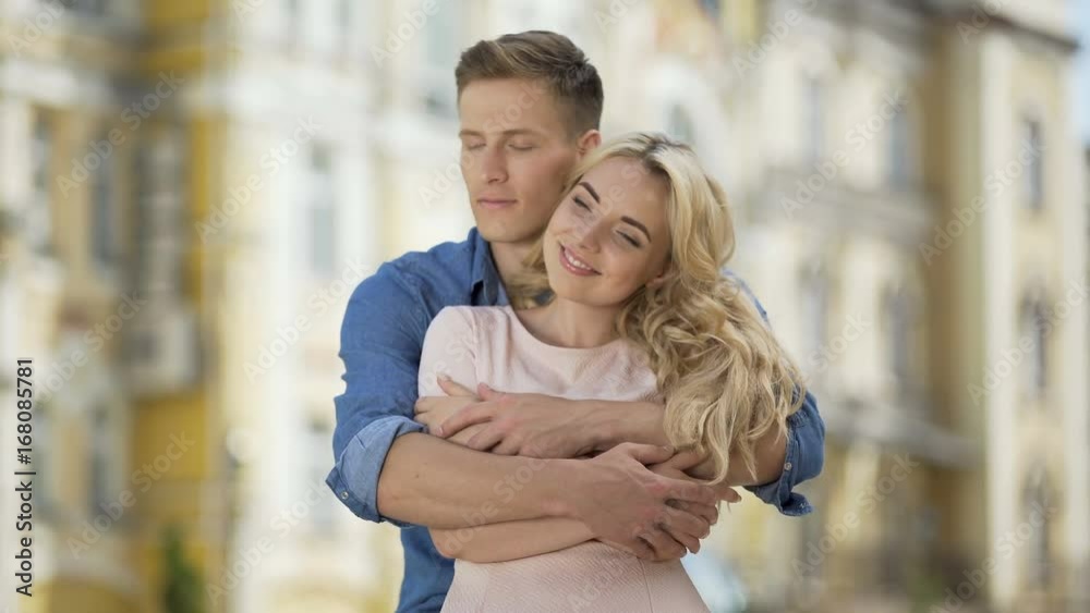 Male hugging his girlfriend from behind, kissing his sweetheart, tenderness Male hugging his girlfriend from behind, kissing his sweetheart, tenderness