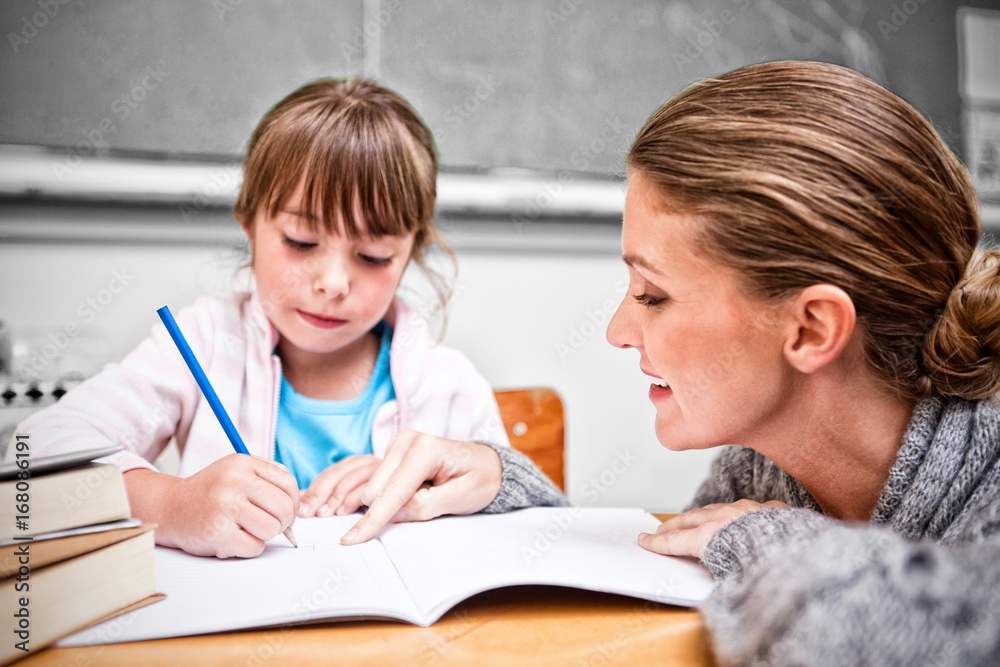 Schoolgirl writing with her teacher in classroom Schoolgirl writing with her teacher in classroom