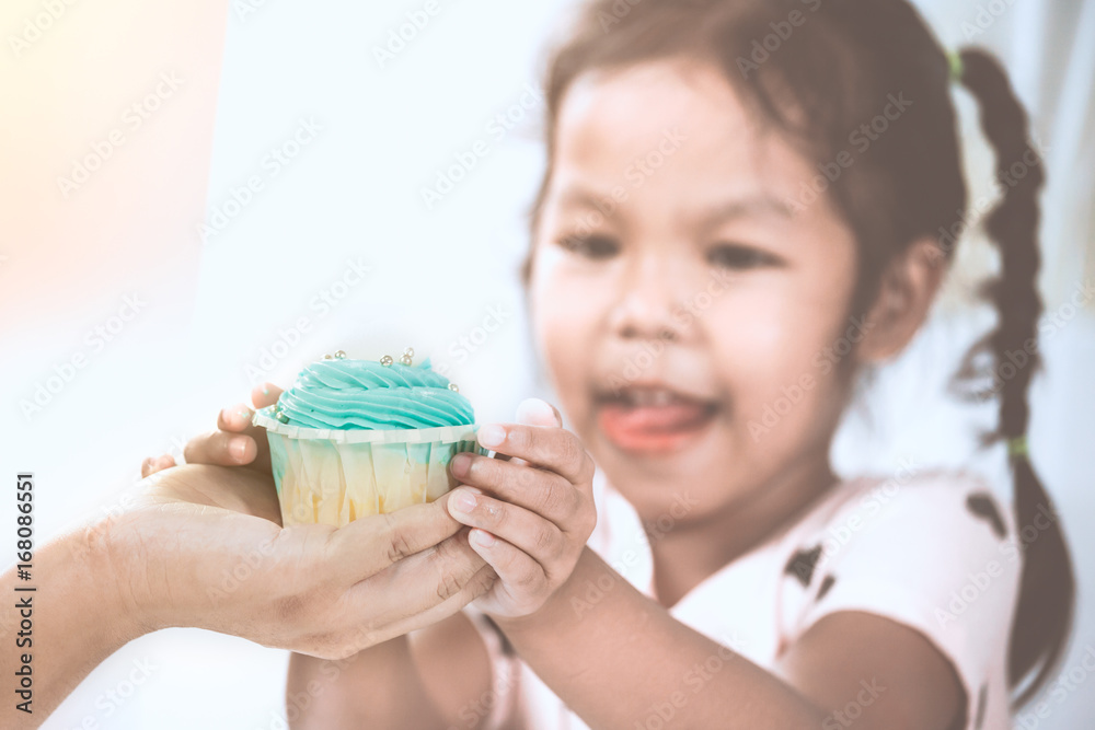 Mother give delicious blue cupcake to child girl and holding together in vintage color tone Mother give delicious blue cupcake to child girl and holding together in vintage color tone