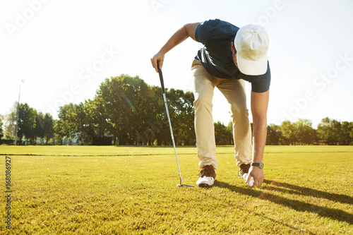 Young male golfer placing golf ball on a tee