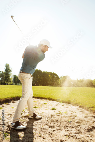 Male golfer hitting ball out of a sand trap
