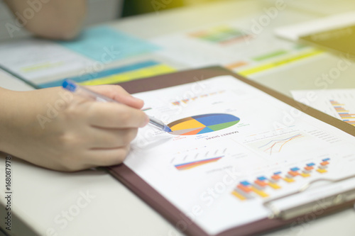 young business women with pen pointing on business document during analysis and planning of market share pie chart at workplace. business concept