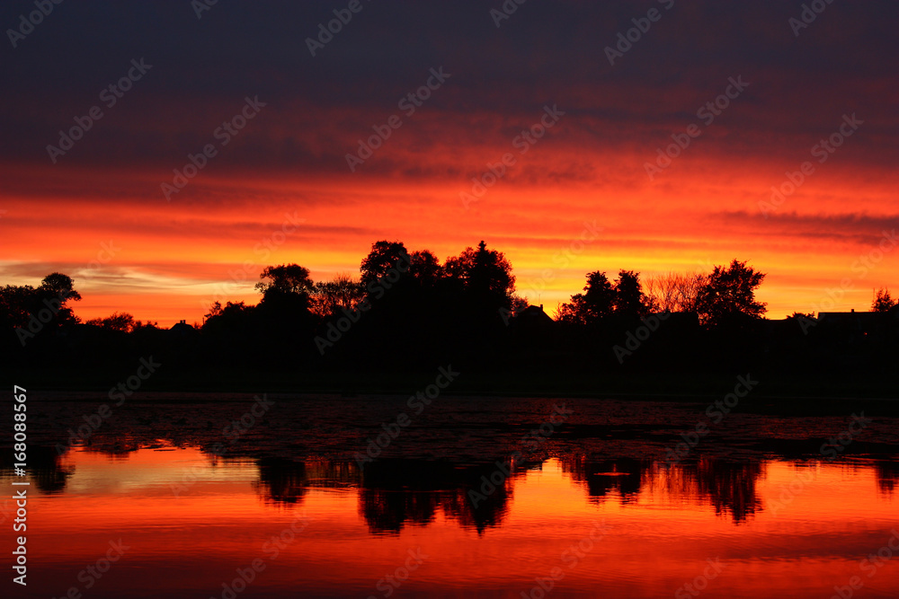 Sunset in red tones./At sunset of a cloud and lake water were partially painted in red tone.