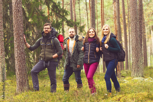 Young happy friends walking in forest and enjoying a good autumn day. Camp, tourism, hiking, trip, concept. © Acronym
