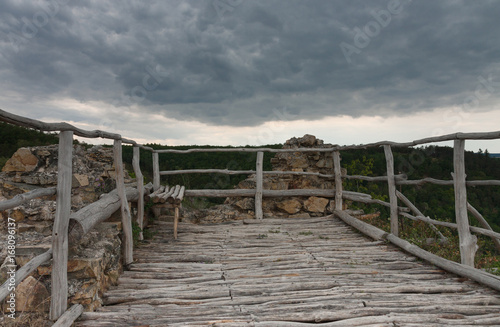 Wooden benche on castle ruins  in backgrounds is cloudy sky.