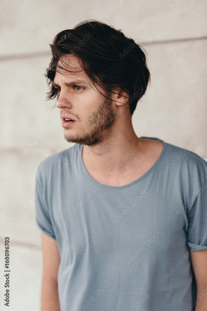 Handsome beautiful young man outdoor. Charming and amazing look.  Fashionable messy hairstyle. Slight beard with little moustache. Outdoor in  the city. Looking at something seriously. Stock Photo | Adobe Stock