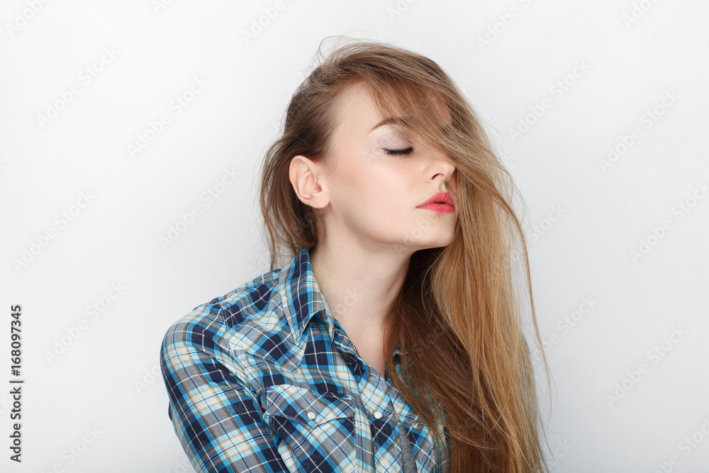 Beauty portrait of young adorable fresh looking blonde woman with hair chaos in blue plaid shirt. Emotion and facial expression concept. Beauty portrait of young adorable fresh looking blonde woman with hair chaos in blue plaid shirt. Emotion and facial expression concept.