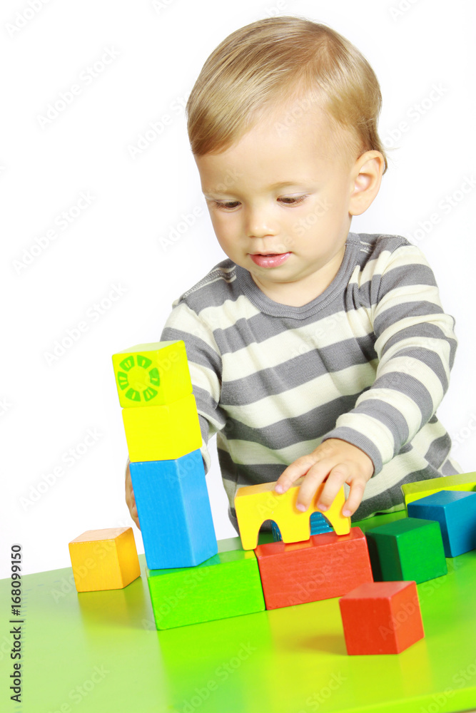 Ein einjähriger Junge spielt mit Holzspielzeug Ein einjähriger Junge spielt mit Holzspielzeug