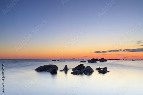 Several rocks in quiet sea at sunset © RistoH