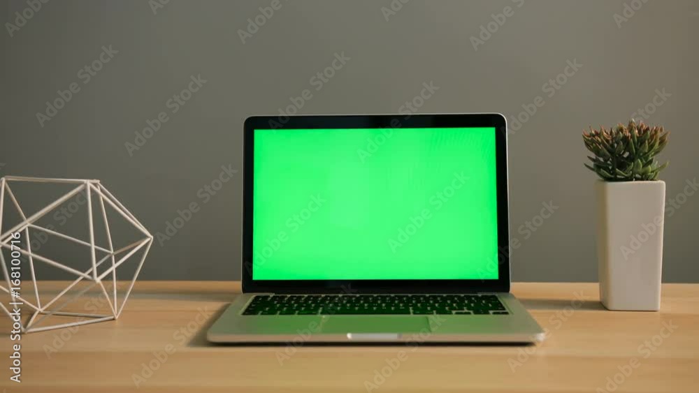 View of laptop with green screen on the table. Chroma key. Close up shot.