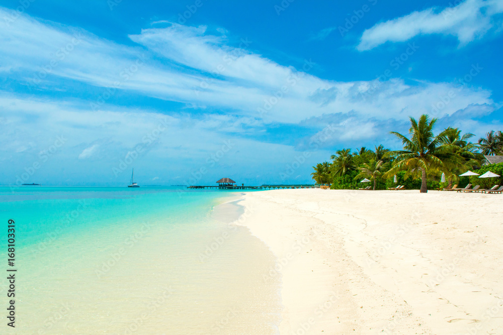 Beautiful sandy beach with sunbeds and umbrellas in Indian ocean, Maldives island