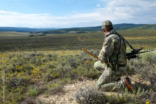 A kneeling camouflaged hunter scans for prey