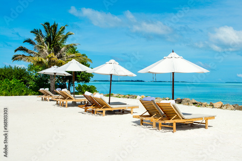 Beautiful landscape with sunbeds and umbrellas on the sandy beach  Maldives island