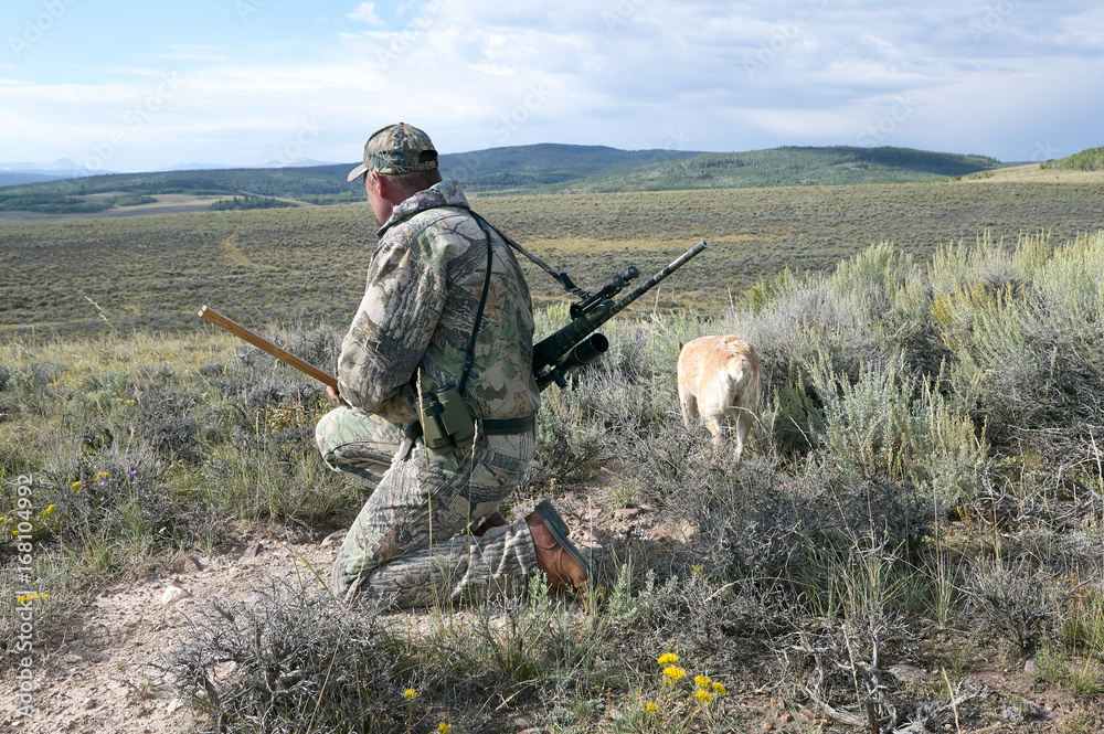Hunter in camouflage scanning an arid landscape