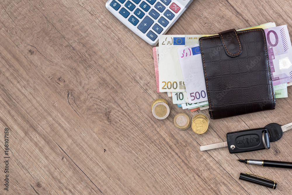 euro in purse with calculator and coin on desk.
