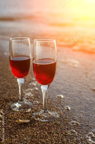 Two red wine glasses in front of the setting sun.