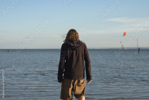 Man in a hooded sweatshirt wading in the sea