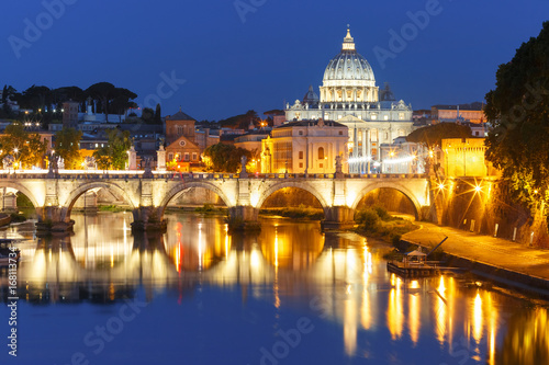 Fototapeta Saint Angel bridge and Saint Peter Cathedral with a mirror reflection in the Tiber River during morning blue hour in Rome, Italy
