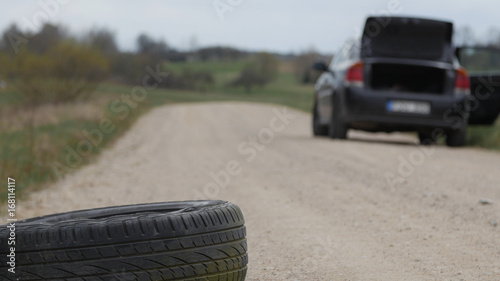 Used old tire eliminated at roadside.Black car in the background . Nature pollution.