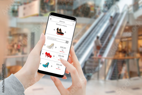 Woman buying heels online on smartphone in shopping mall