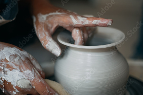 Potter works at pottery wheel  dirty woman hands