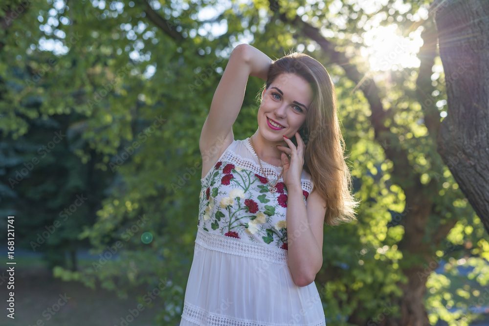 Beautiful girl posing in the street on the background of green trees Beautiful girl posing in the street on the background of green trees