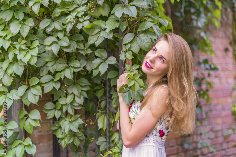 girl on the background of a wall with green foliage girl on the background of a wall with green foliage