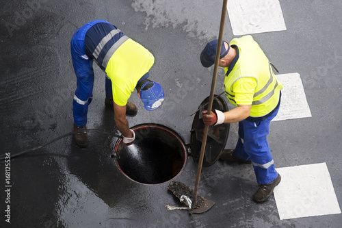 sewer line drainage  by utilities workers with hose with pressurized water photo