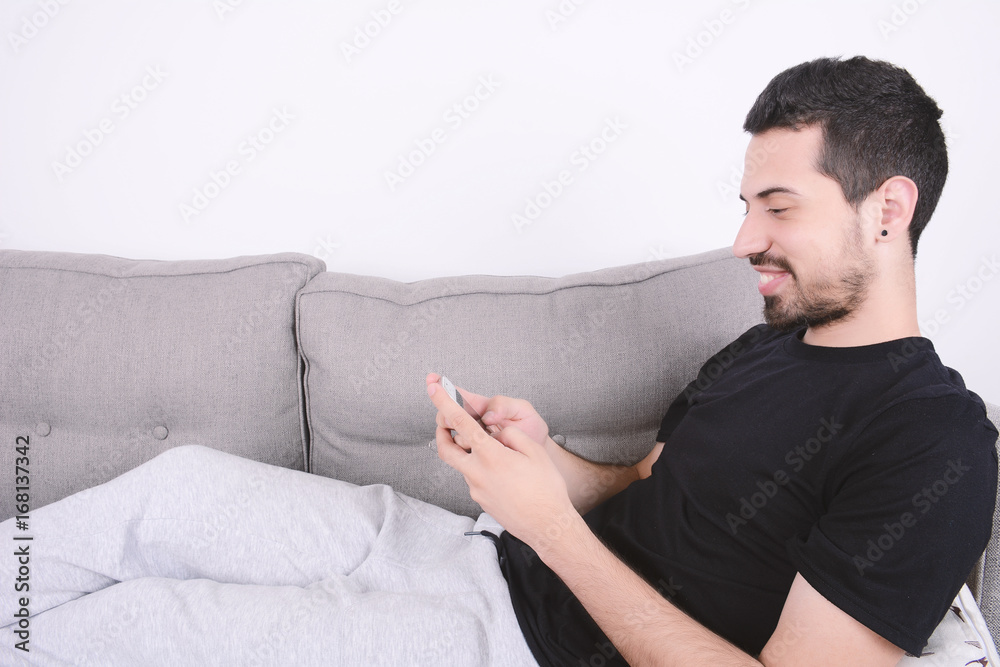 Man using smartphone on couch.