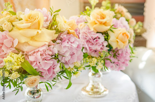 Big bouquet of pink hydrangeas and yellow roses stands on dinner table