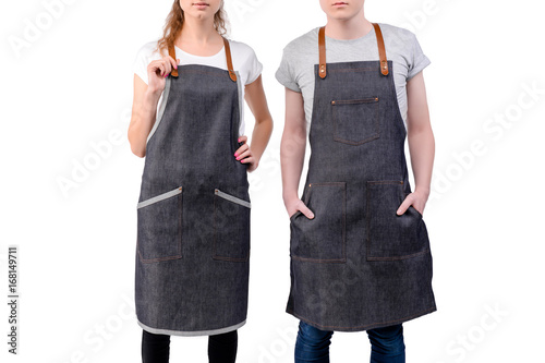 Billede på lærred Young chefs or waiters man and woman posing, wearing aprons isolated on white background