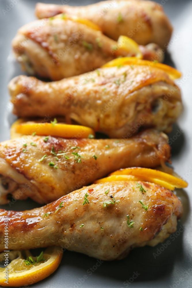 Delicious roasted chicken drumsticks with lemon on plate, closeup Delicious roasted chicken drumsticks with lemon on plate, closeup
