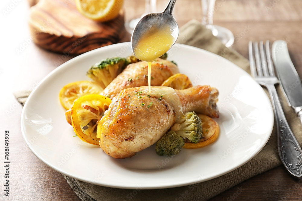 Pouring delicious sauce onto roasted chicken drumsticks on plate Pouring delicious sauce onto roasted chicken drumsticks on plate