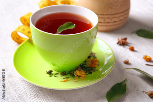 Cup of tea with brew on wooden table. Weight loss concept