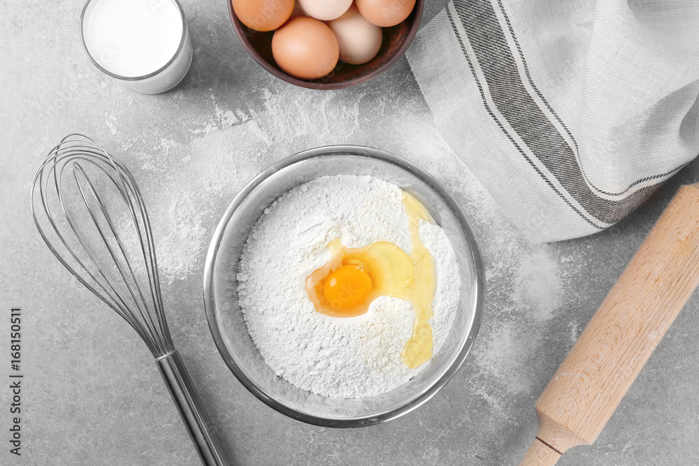 Metal bowl with flour and egg on kitchen table Metal bowl with flour and egg on kitchen table