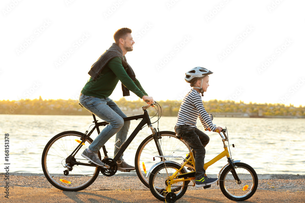 Dad and son riding bicycles near water front
