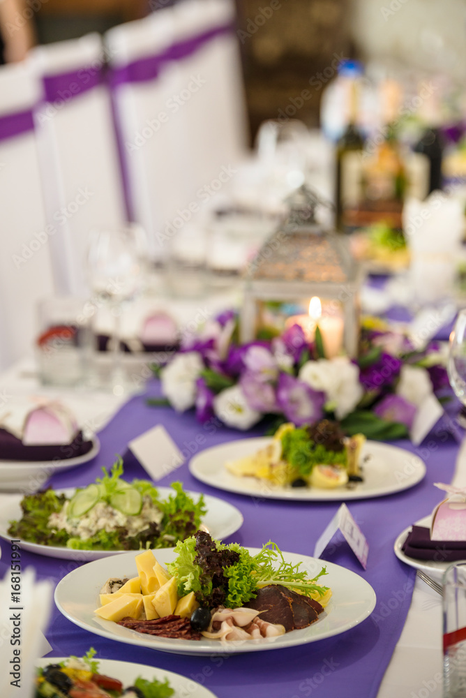 wedding banquet table in white and purple colours decorated lanterns and candles