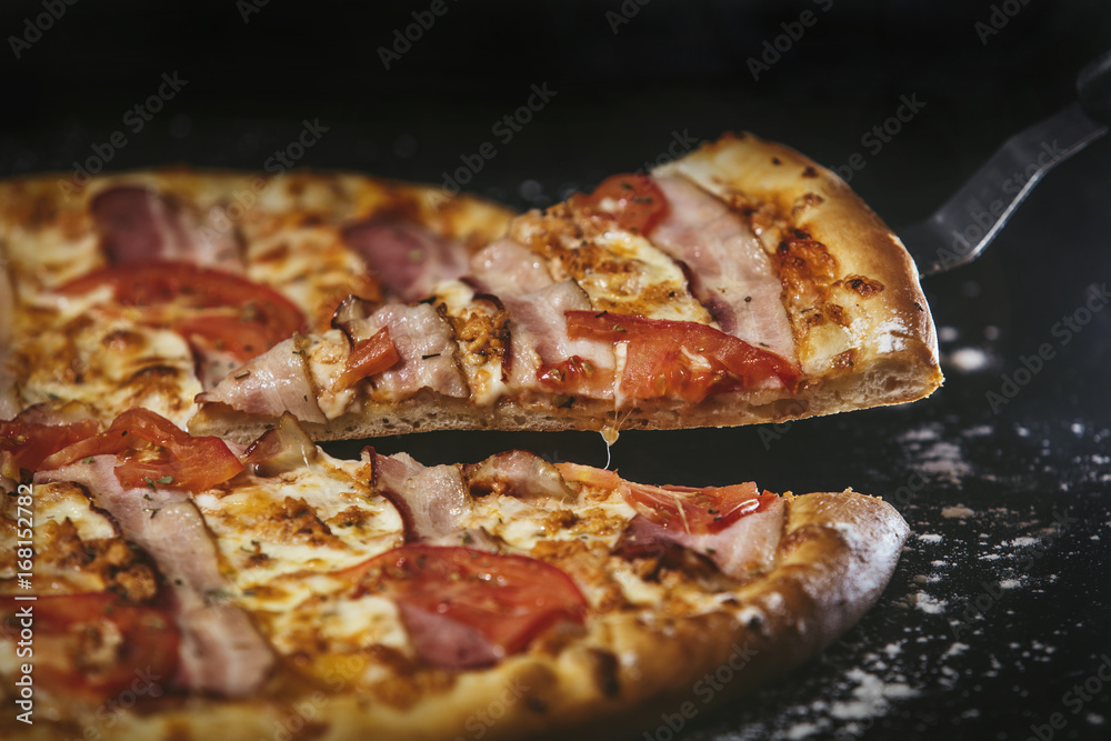 Delicious pizza fresh hot closeup on black table with scattered flour Delicious pizza fresh hot closeup on black table with scattered flour