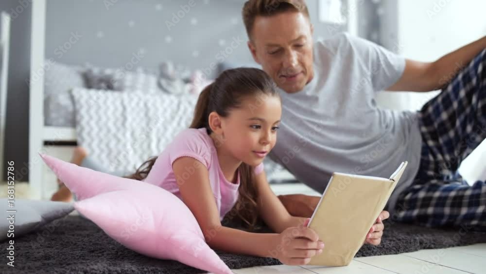 Pleasant little girl reading a book with her father Pleasant little girl reading a book with her father