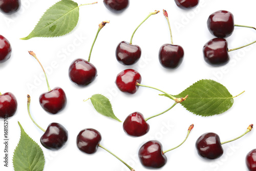 Fresh sweet cherries and green leaves on white background