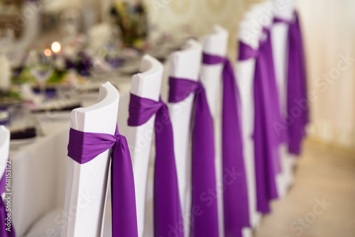 Photography wedding chairs in covers and decorated purple ribbon and bows