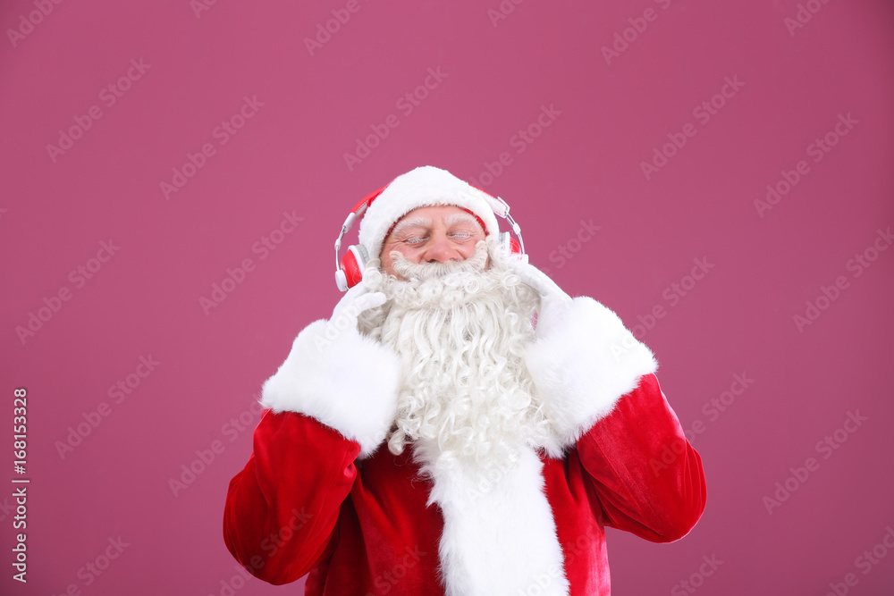 Santa Claus listening to music on color background