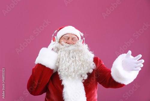 Santa Claus listening to music on color background