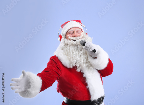 Santa Claus singing Christmas songs on color background