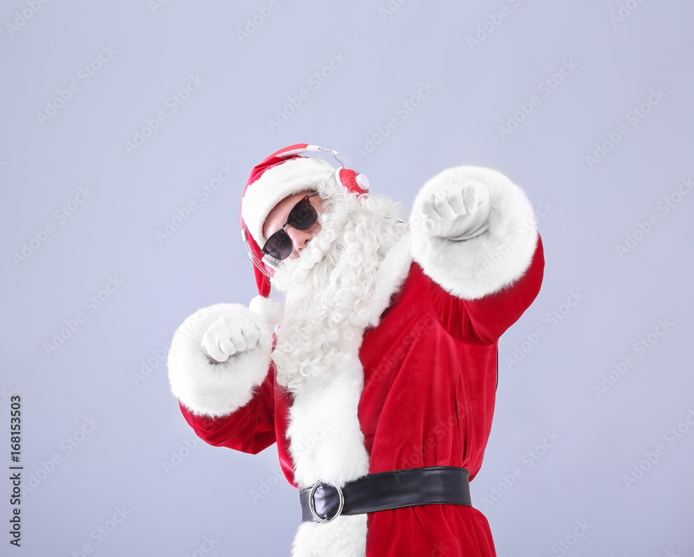 Santa Claus listening to music on light background