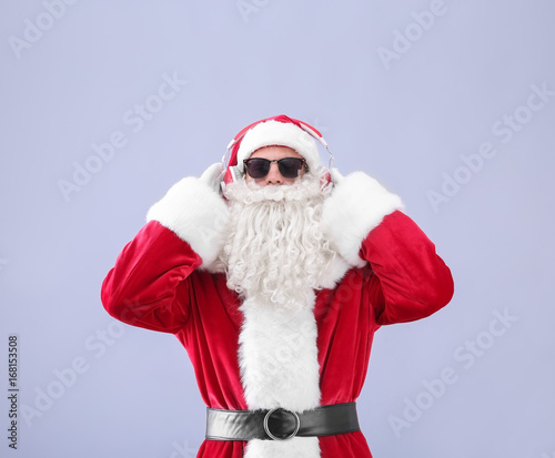 Santa Claus listening to music on light background