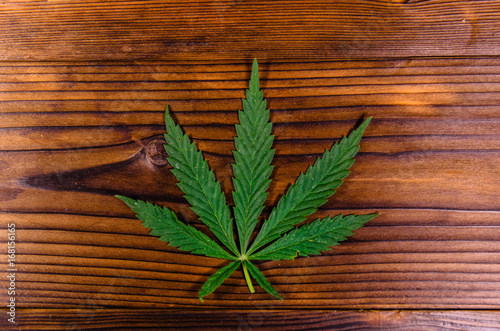 Fototapeta Naklejka Na Ścianę i Meble -  Leaf of the cannabis plant on wooden table. Top view