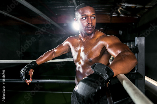 Muscular attractive african american male athlete fighter in the corner of a boxing ring