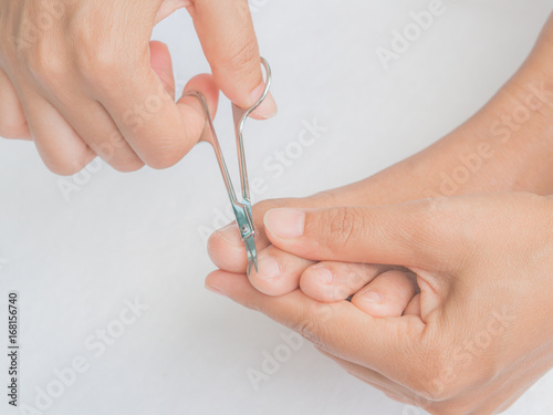 Closeup attractive young woman cutting her feet nails. Health care and beauty concept.