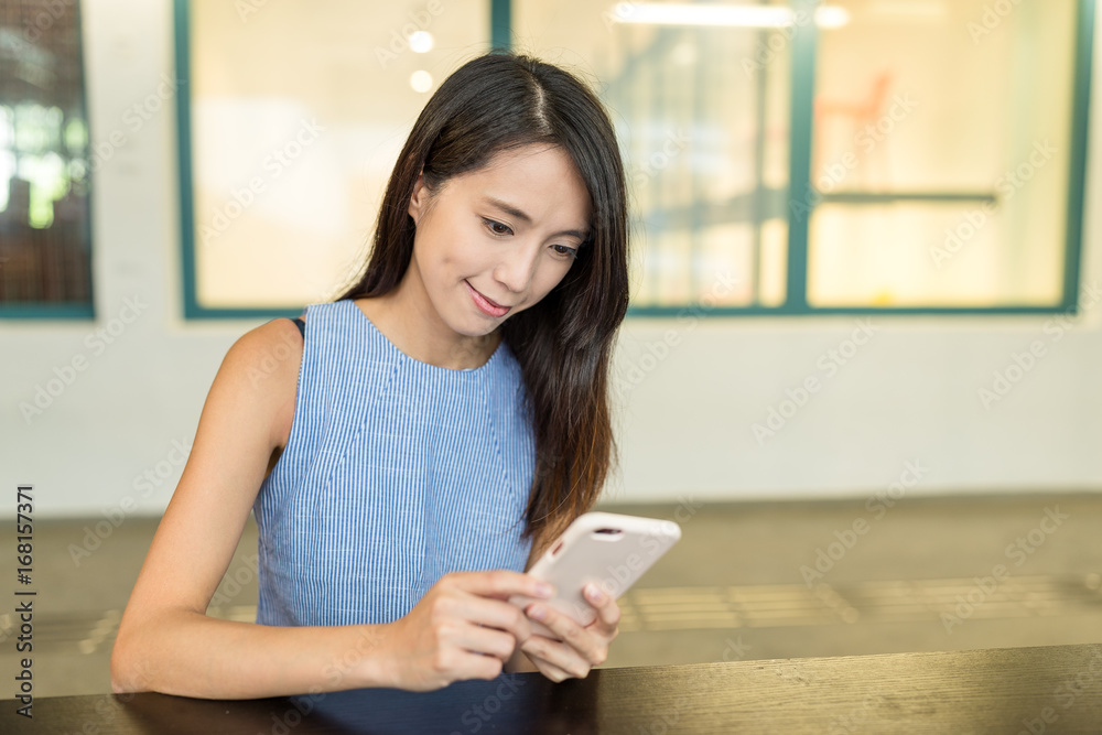 Woman looking at mobile phone and sitting in the outdoor cafe